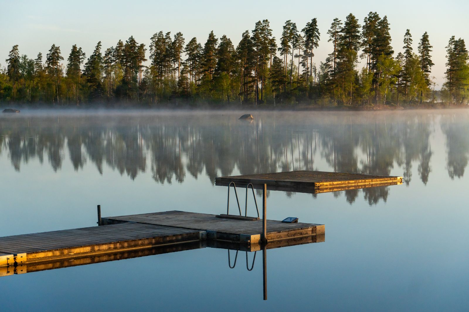 A wooden pier reaching into calm water at first light